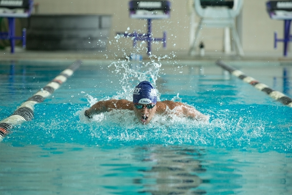 Male student swimming in pool