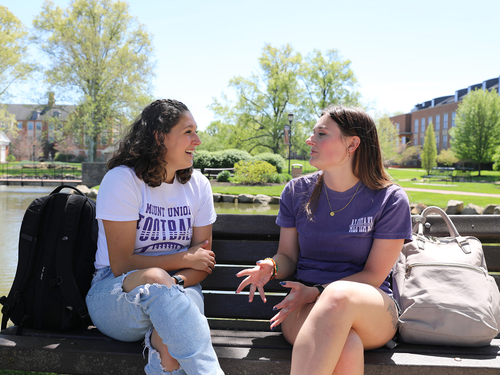 Two students sitting on a bench alongside the Campus Lakes