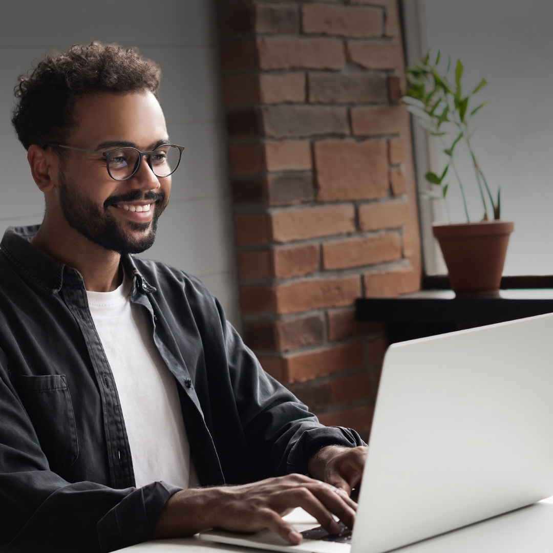 Professional smiling in front of a computer while taking an online course