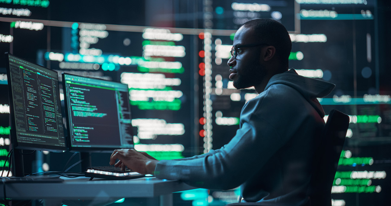 cybersecurity professional working in front of computer monitors.  
