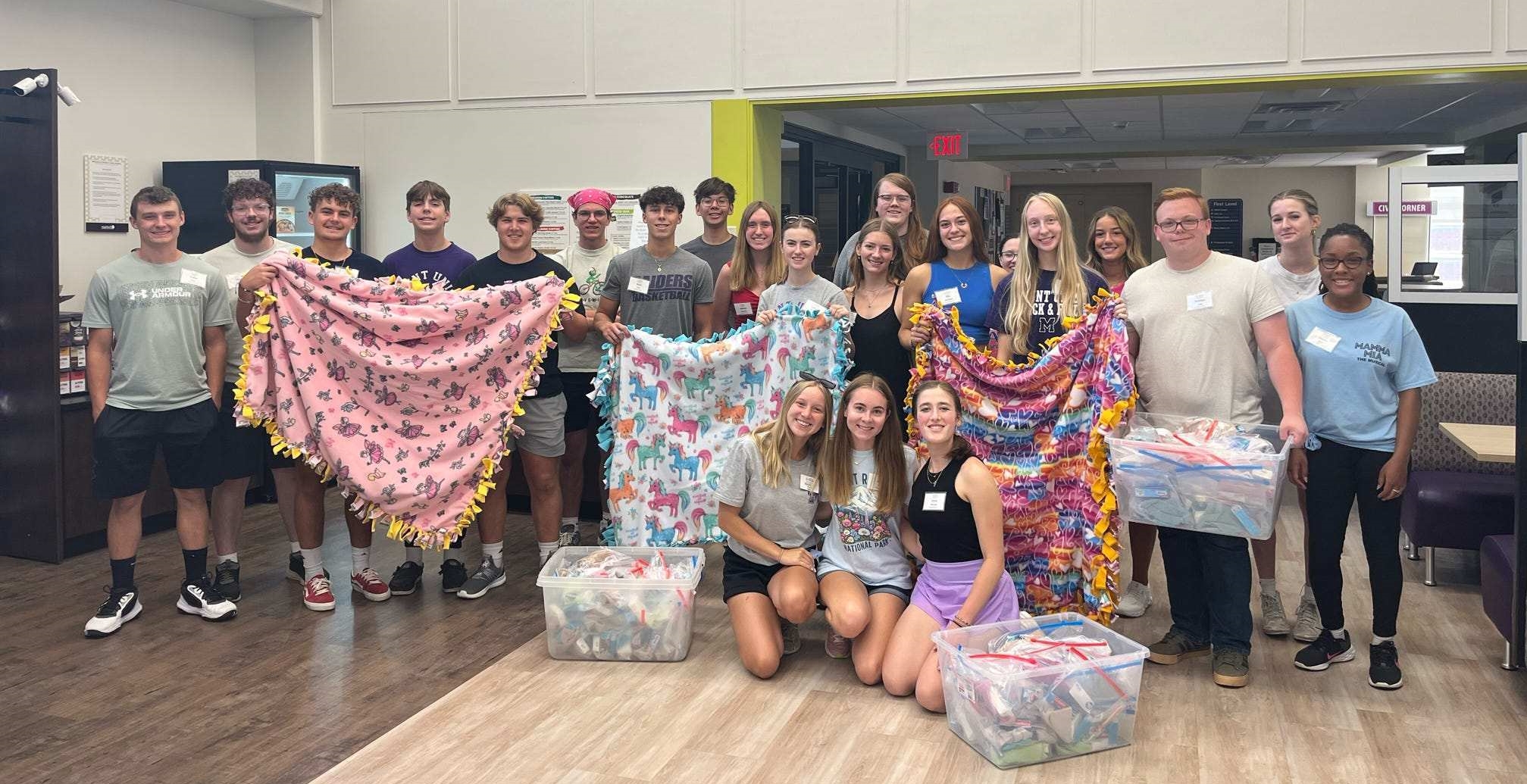 students holding handmade blankets