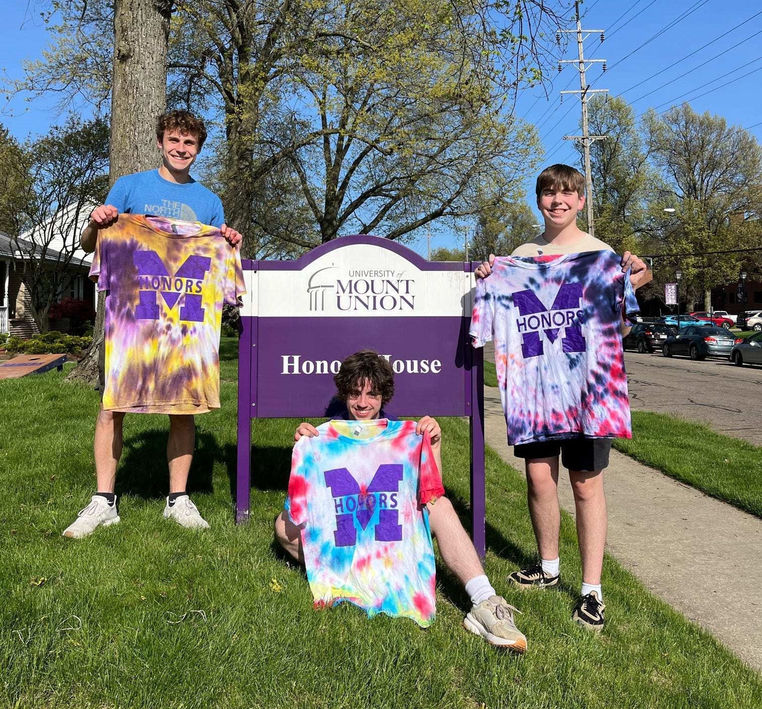 students holding t-shirts in front of honors house