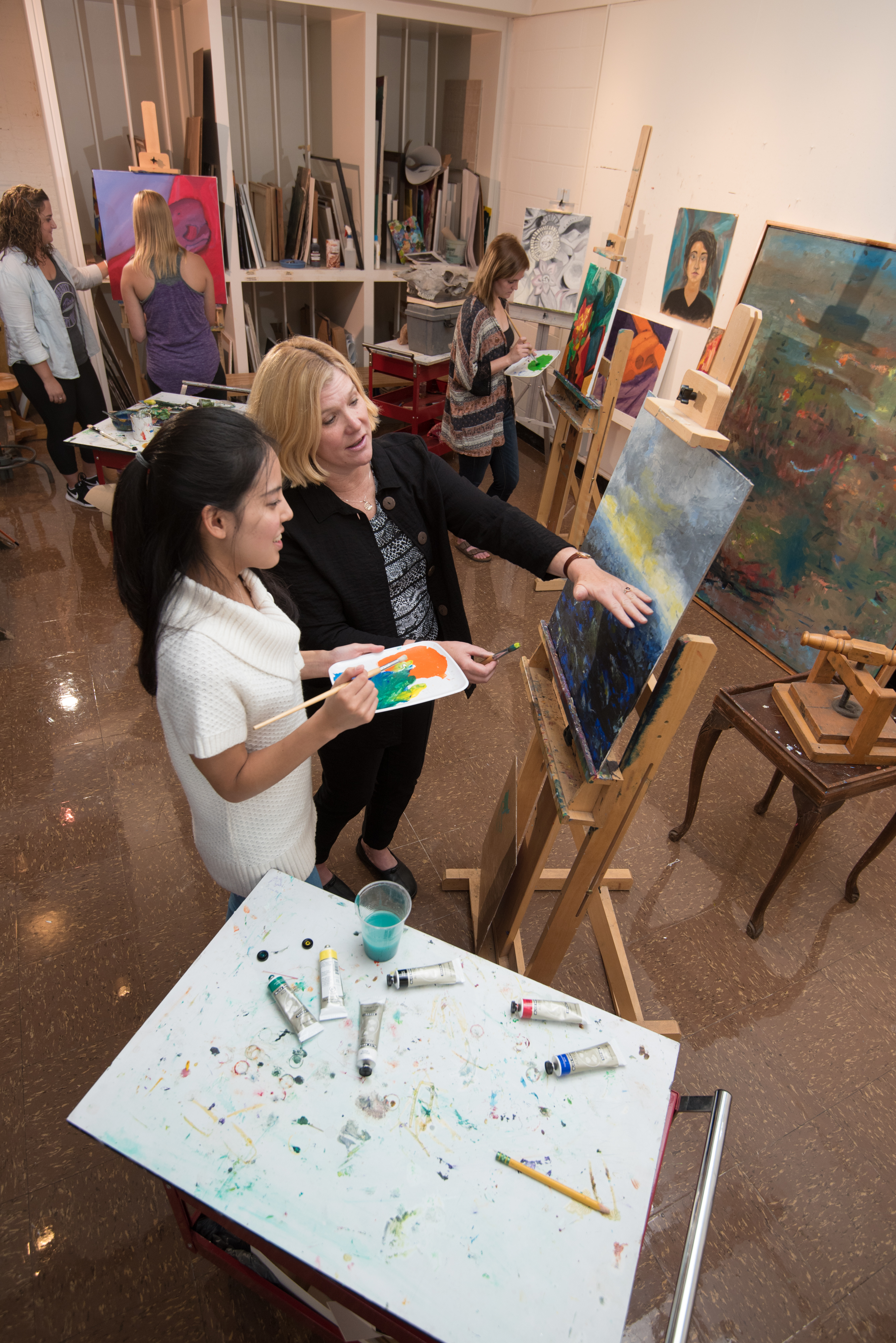 Art student and professor working on a painting project 