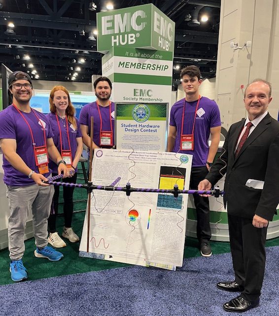 engineering students posing with prototype at conference