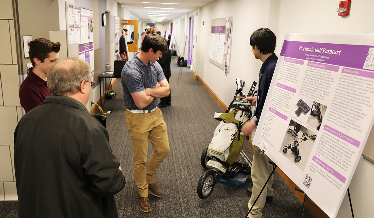 student displaying golf cart project