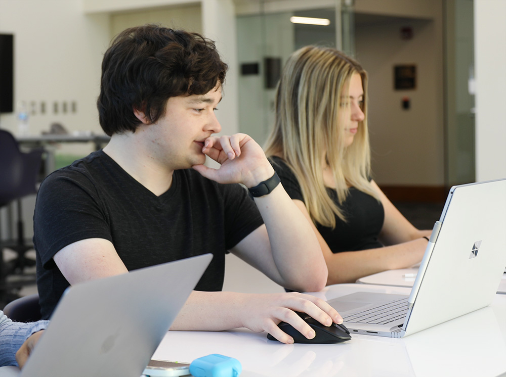 two students working on laptops