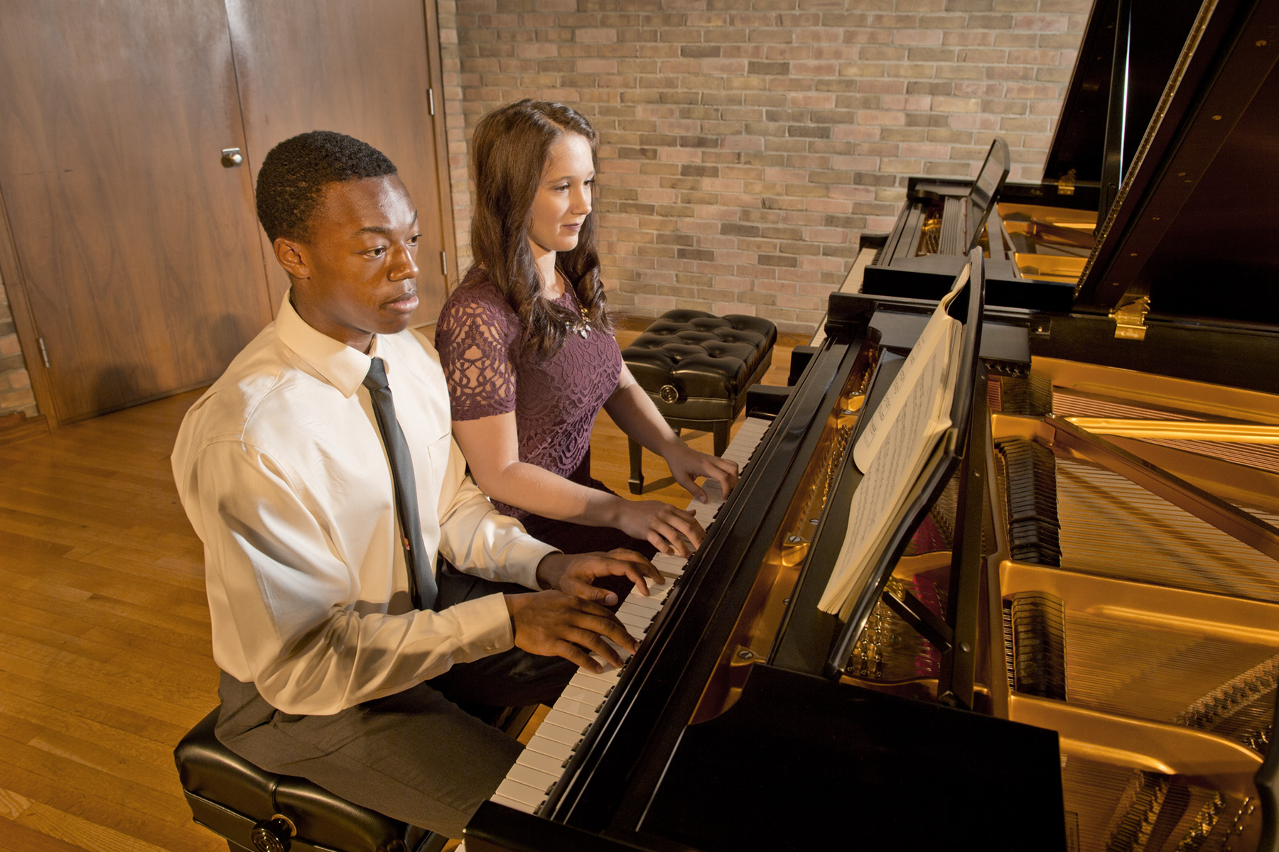 two students playing piano