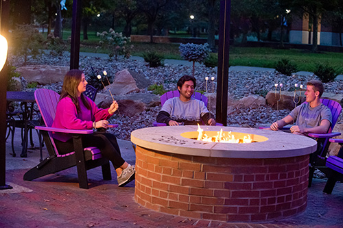 student sitting around fire pit