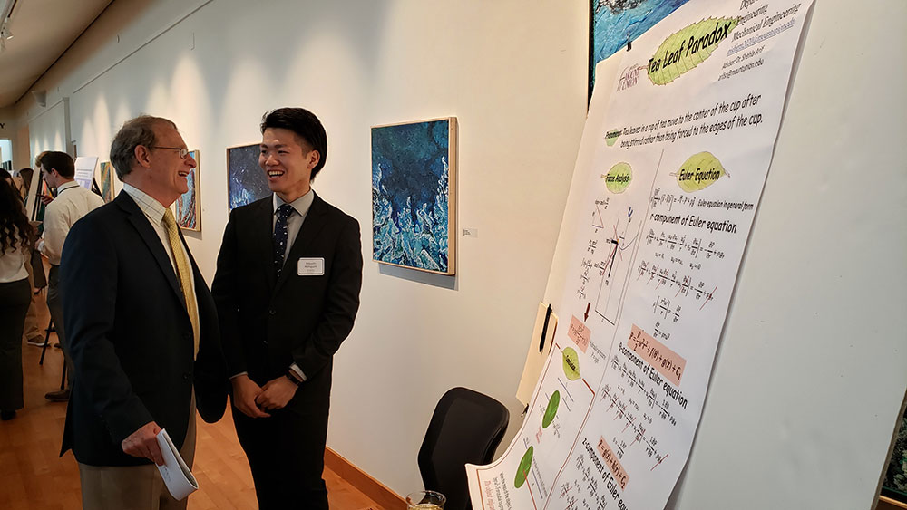 Student presenting research poster to faculty member during SCHOLAR Day