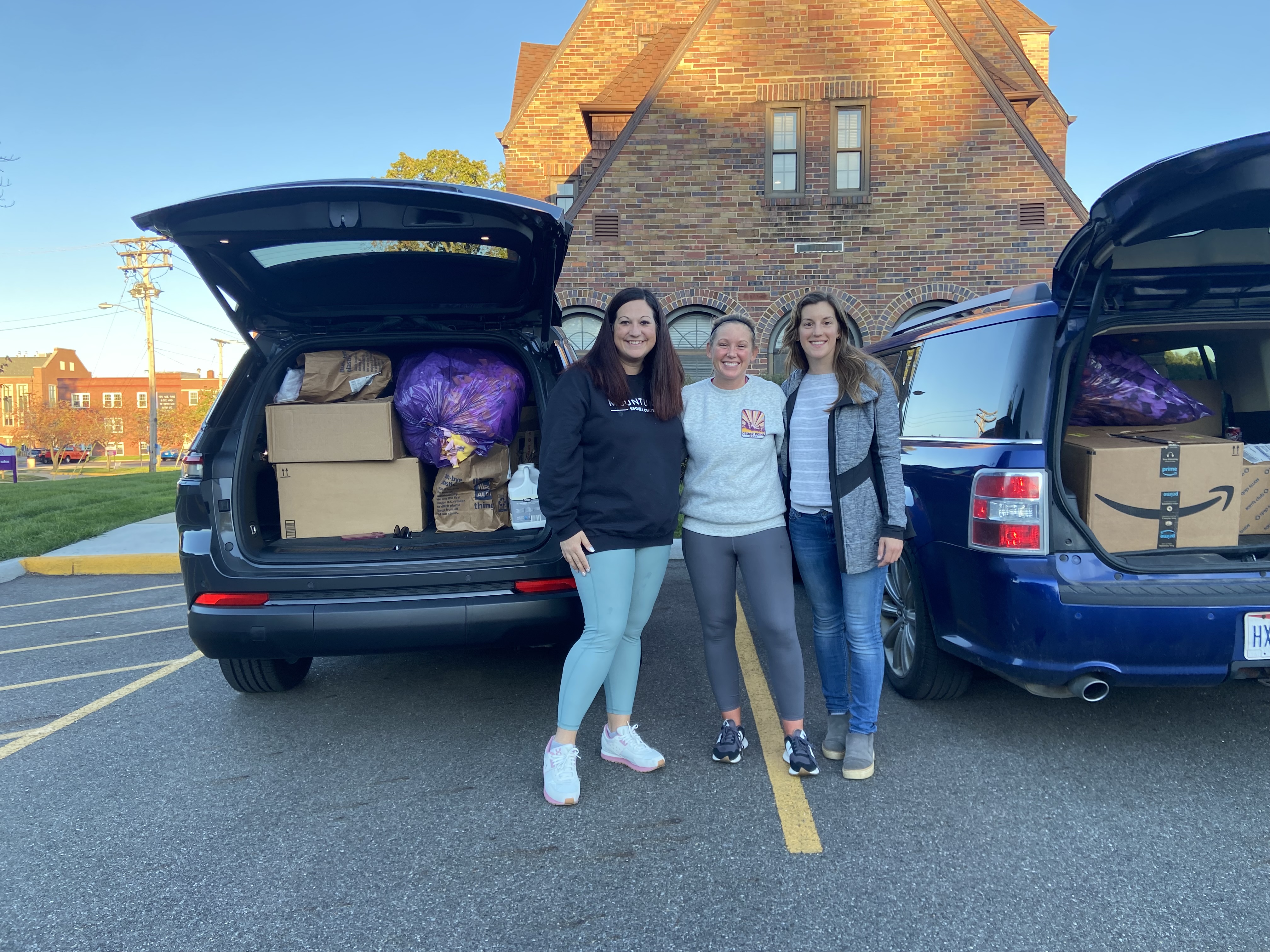 trio of women standing in front of boxes of donations to hurricane relief